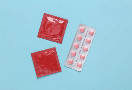 contraceptives. Condoms and birth control pills on blue background.の写真素材