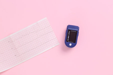 Pulse oximeter with cardiogram on a pink background. health care concept. top view