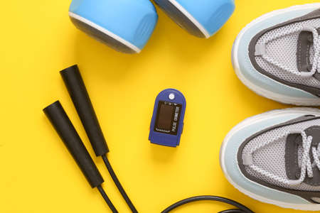 health care. Healthy lifestyle concept. Skipping rope, dumbbells and sneakers with pulse oximeter on...