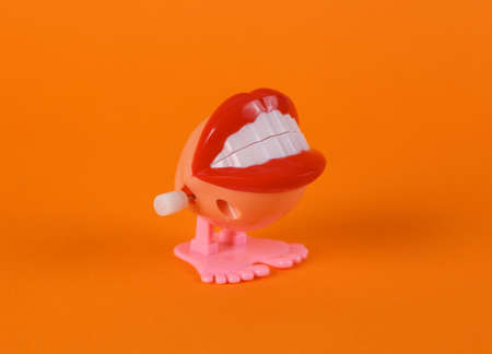 Clockwork halloween toy monster lips on orange background