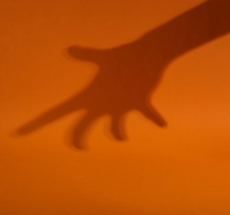Minimal halloween concept. Hand shadow on orange background