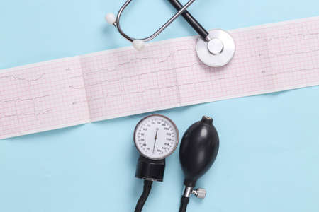 Stethoscope with a medical tonometer and a cardiogram on a blue background. Diagnosis of cardiovascular diseases. top viewの写真素材