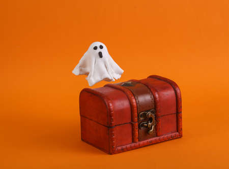 Ghost guarding a pirate chest on an orange background. halloween conceptの写真素材