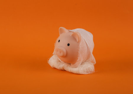 Mummy piggy bank wrapped in bandages on orange background. Trick or treat. Halloween still lifeの写真素材