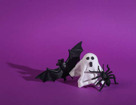 Little ghost with a spider and bat on purple background. Halloween still lifeの写真素材