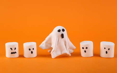 Ghost and halloween marshmallows with faces on orange backgroundの写真素材