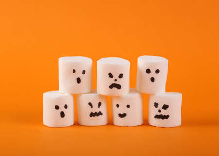 Halloween marshmallows with face on orange backgroundの写真素材