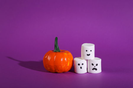 Pumpkin with halloween marshmallows on purple backgroundの写真素材