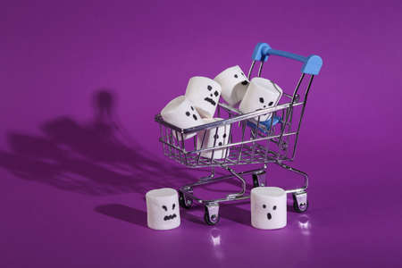 Shopping cart with Halloween marshmallows on purple backgroundの写真素材