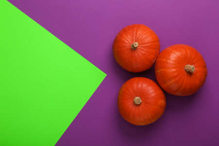 Orange pumpkins on green-purple background. Halloween minimal still life. top view