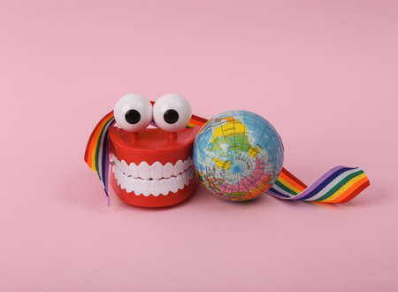 International day against homophobia. Clockwork jaw with eyes wrapped with rainbow ribbon and globe...