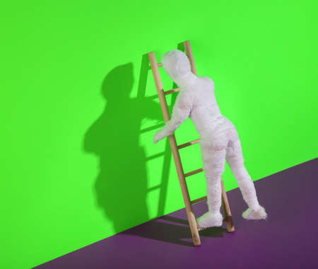 Wooden ladder with mummy doll on purple green background. Minimal halloween layout.の写真素材