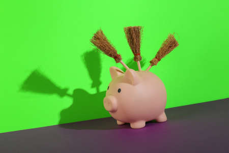 Piggy bank with witch's brooms on a purple-green background. creative halloween layoutの写真素材