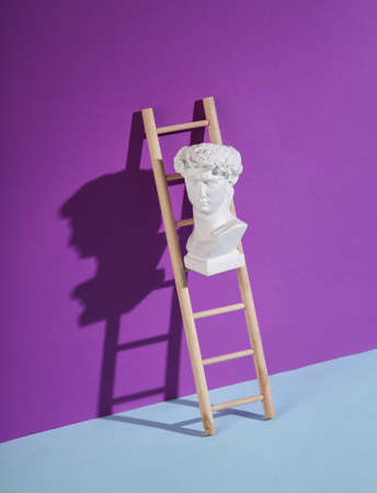 Wooden ladder with David bust on purple background. minimum layout. Business, leadership concept, career growthの写真素材