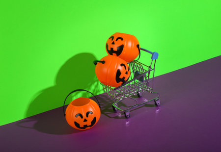 Shopping cart with halloween buckets on green purple background. Creative halloween layout, sale, shopping conceptの写真素材