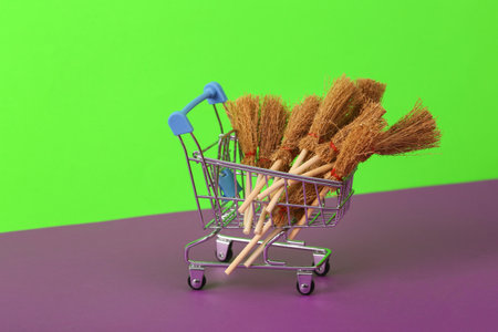 Shopping cart with Halloween witch brooms on green purple backgroundの写真素材
