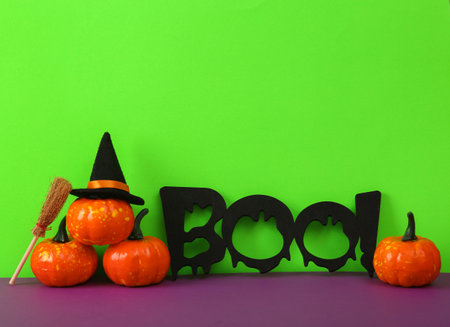 Halloween still life with plastic pumpkins and word boo! on a green-purple backgroundの写真素材