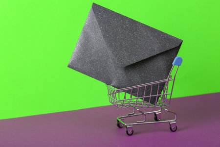 Shopping trolley with envelope on green purple background