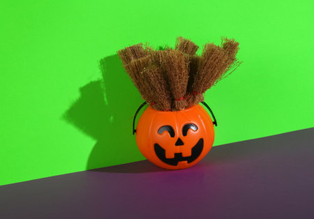 Halloween bucket pumpkin for candy with brooms on green purple background. Trick or Treatの写真素材