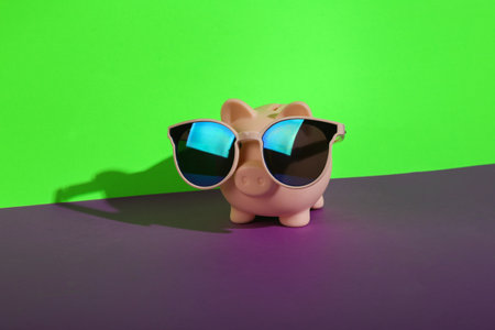 Piggy bank with sunglasses on green purple backgroundの写真素材
