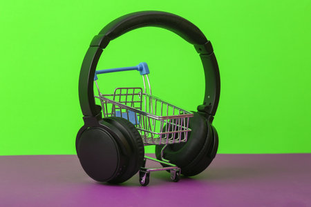 Shopping cart with stereo headphones on green purple backgroundの写真素材
