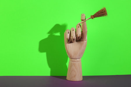Wooden hand holds witch's hat on green-purple background. Minimal halloween still lifeの写真素材