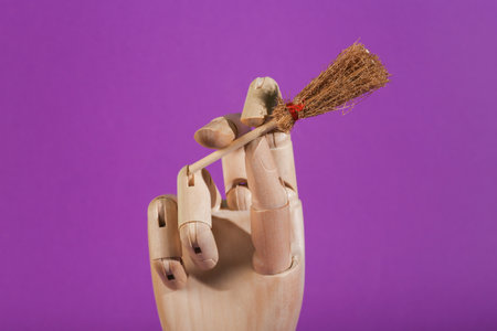 Wooden hand holds witch's hat on purple background. Minimal halloween still lifeの写真素材