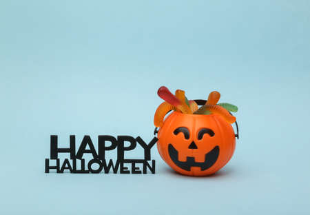 Halloween candy bucket with jelly worms and word happy halloween on a blue background. Trick or Treatの写真素材