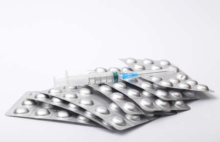 Metal blisters of pills with syringe isolated on white backgroundの写真素材