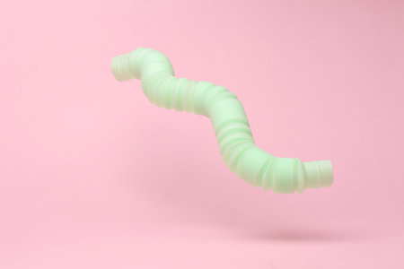 Antistress sensory pop tube toy flying in antigravity on pink background with shadow. Pastel color trend. Levitation object in the air. Creative minimal layoutの写真素材