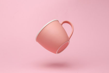 Pink ceramic cup flying in antigravity on pink background with shadow. Levitation object in the air. creative minimal layoutの写真素材