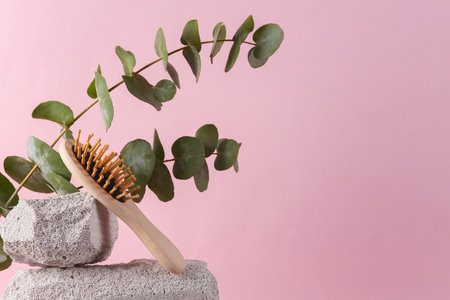 Woioden hair brush on stone with eucalyptus branch. beauty concept. haircare. Modern still life, product photo. Aesthetic minimalist composition.の写真素材