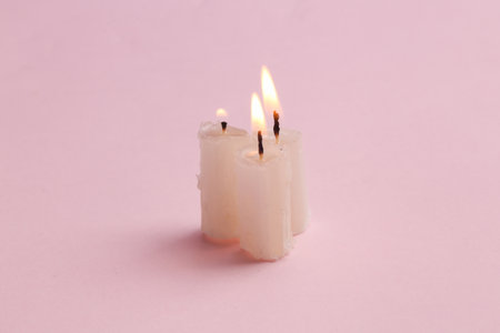 Three flaming candles on a pink background