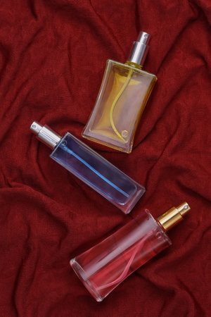 Glass bottles of perfume on red crumpled silk background