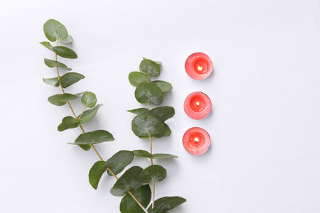 Flaming aroma candles with eucalyptus branches on white background. aroma therapy. top viewの写真素材