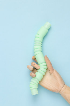 Puppet hand holding Pop tube, Sensory anti-stress toy on blue backgroundの写真素材