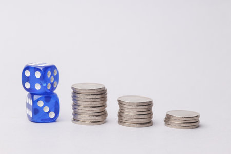 Dice with stack of coins on white background.の写真素材