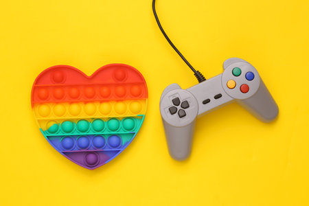 Antistress pop it sensory toy with video game gamepad on yellow background