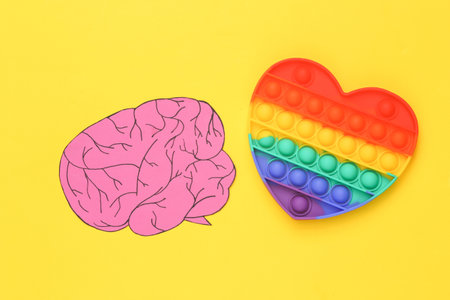 Popular Pop it antistress heart shaped toy with brain on yellow background