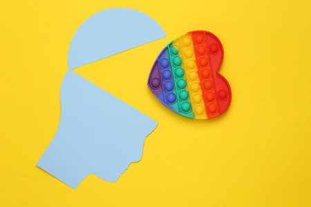 head silhouette with popular Pop it antistress heart shaped toy on yellow backgroundの写真素材