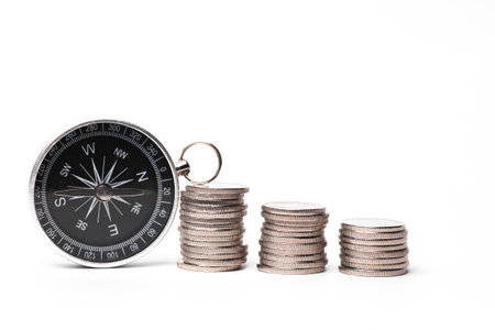 Compass with stack of coins on  white background