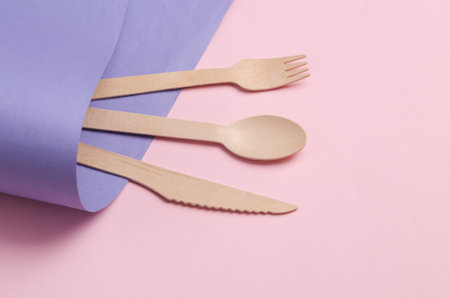 Wooden knife, spoon and fork on purple pink background. Eco productsの写真素材