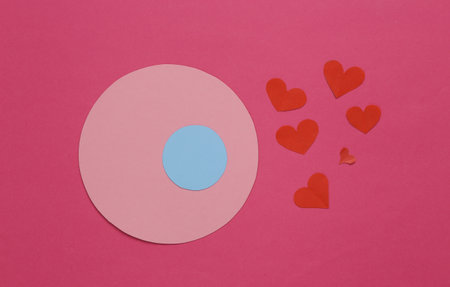 Love, ovulation, conception concept. Egg and paper cut hearts on a pink background
