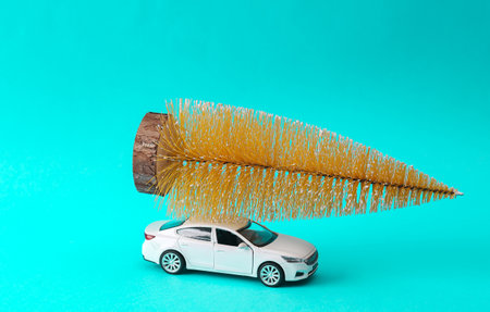 Toy car with decorative miniature Christmas tree on turquoise background. holiday delivery. merry christmasの写真素材