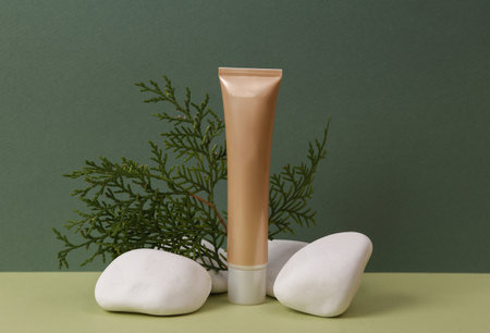 Aesthetic beauty or makeup still life. Foundation cream bottle with stone and herbal twig on two tone green background. natural cosmetics, skincareの写真素材