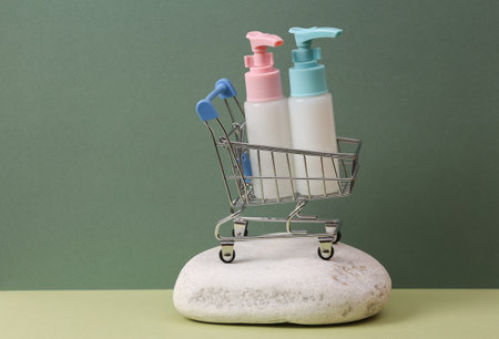 Aesthetic beauty still life. Shopping trolley with Bottles of cream or liquid soap on stone, two...