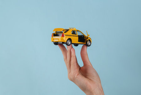 Mini model yellow taxi car in female hand on a blue background.の写真素材