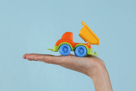 Toy dump truck on female palm, blue background.の写真素材