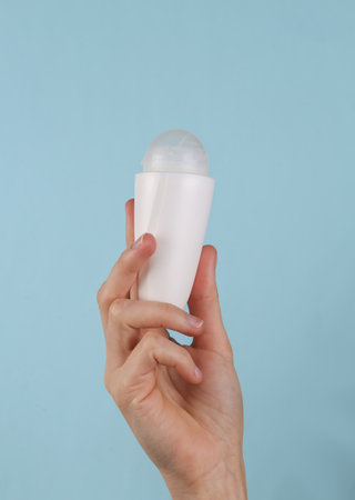 Antiperspirant roll-on stick in female hand on a blue backgroundの写真素材