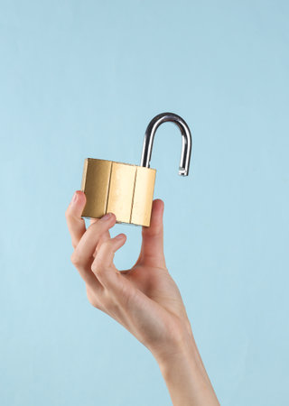 Open metal lock in female hand on a blue background.の写真素材
